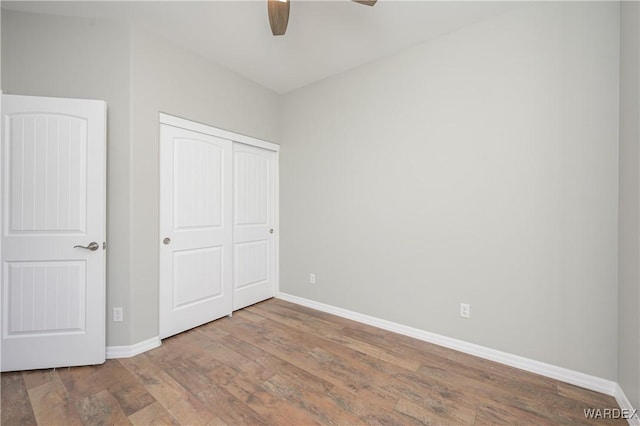 unfurnished bedroom with a ceiling fan, a closet, baseboards, and wood finished floors