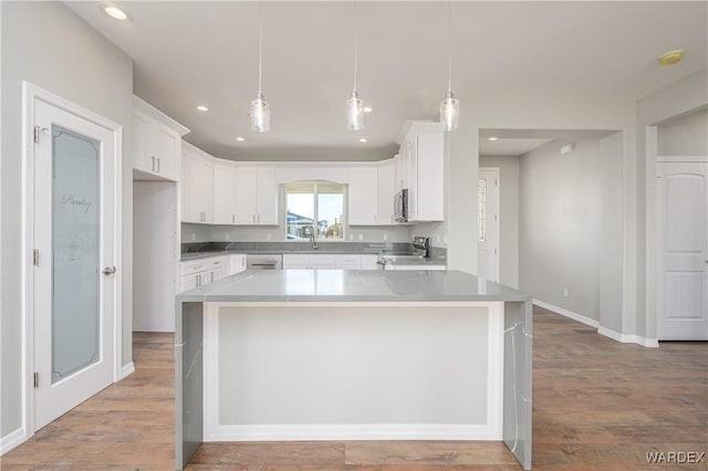 kitchen featuring white cabinets, light countertops, appliances with stainless steel finishes, hanging light fixtures, and a center island