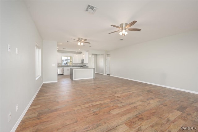 unfurnished living room featuring a ceiling fan, baseboards, visible vents, and dark wood-type flooring