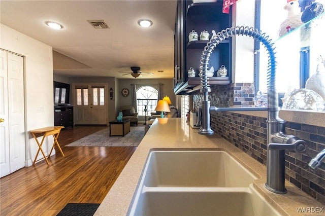 kitchen featuring open shelves, visible vents, a ceiling fan, a sink, and wood finished floors