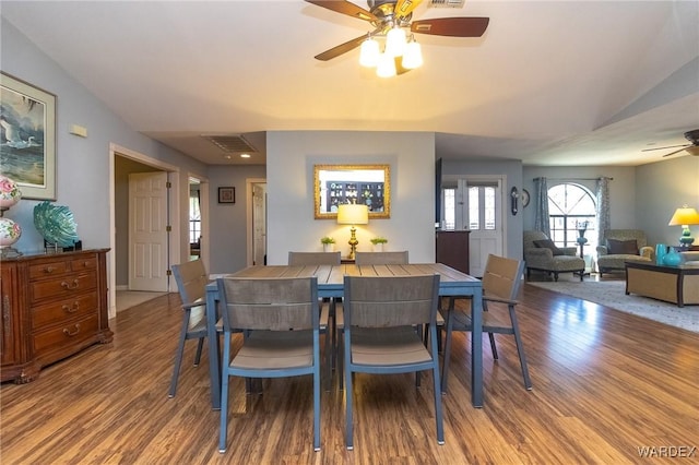 dining space with lofted ceiling, ceiling fan, visible vents, and wood finished floors