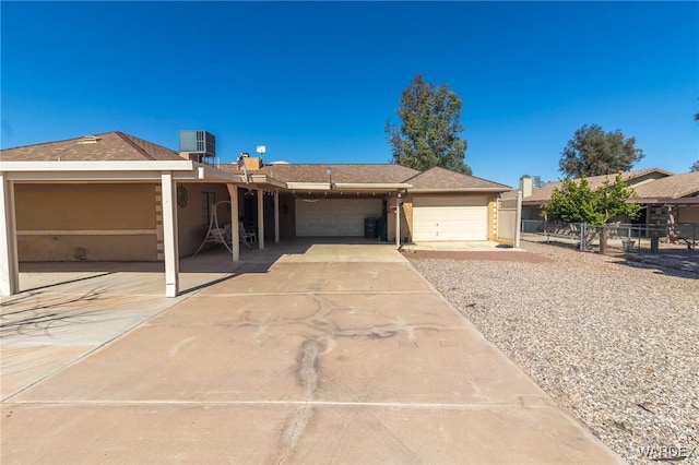 ranch-style house featuring central air condition unit, an attached garage, fence, and stucco siding