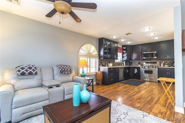 living area featuring light wood finished floors, ceiling fan, visible vents, and baseboards