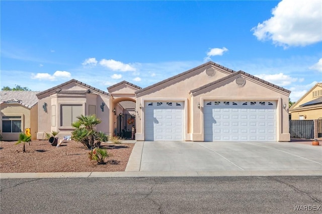 view of front of house featuring concrete driveway, an attached garage, a tiled roof, and stucco siding