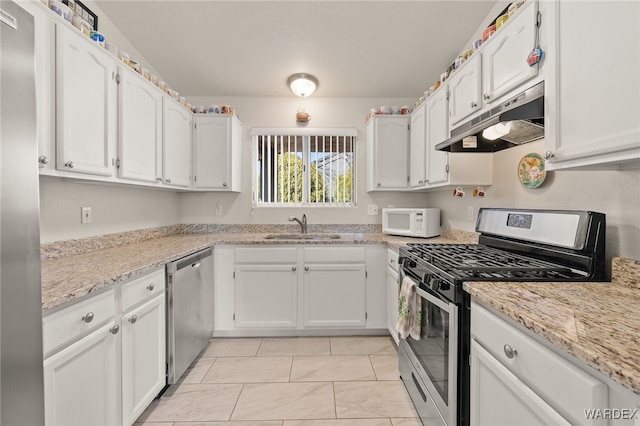 kitchen with light stone counters, stainless steel appliances, white cabinets, a sink, and under cabinet range hood