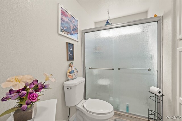 full bath featuring a shower with shower door, toilet, and wood finished floors