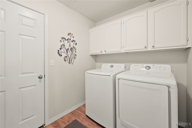 washroom featuring cabinet space, washing machine and dryer, baseboards, and wood finished floors