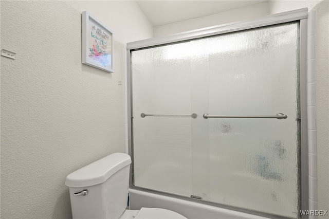 full bath with enclosed tub / shower combo, a textured wall, and toilet