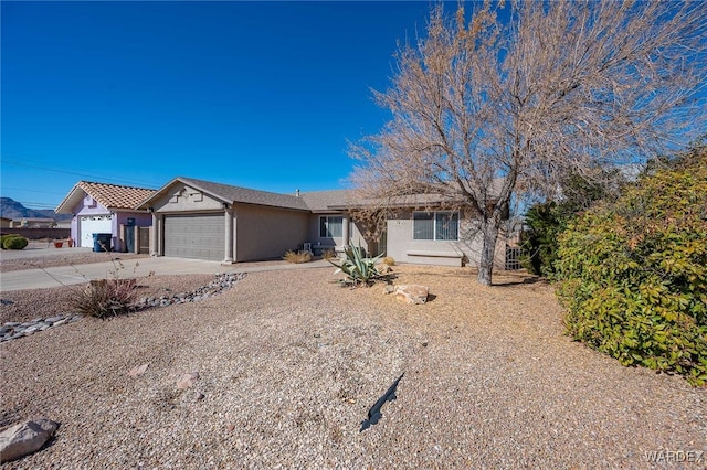 ranch-style house with driveway, an attached garage, and stucco siding