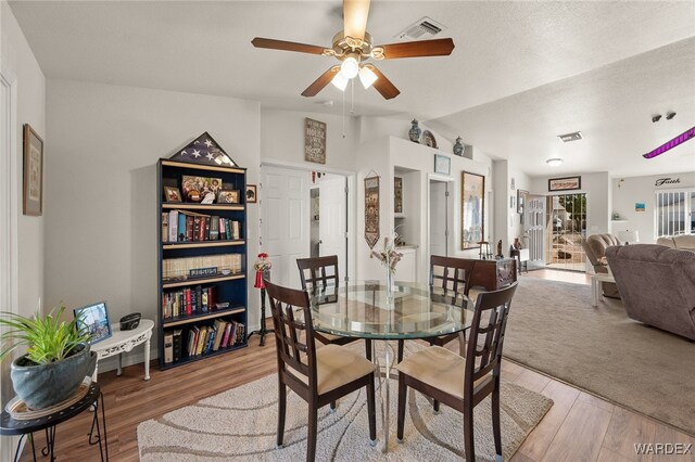 dining room featuring lofted ceiling, wood finished floors, and visible vents