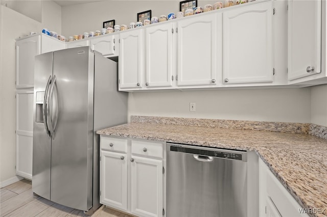 kitchen with light stone countertops, appliances with stainless steel finishes, and white cabinets