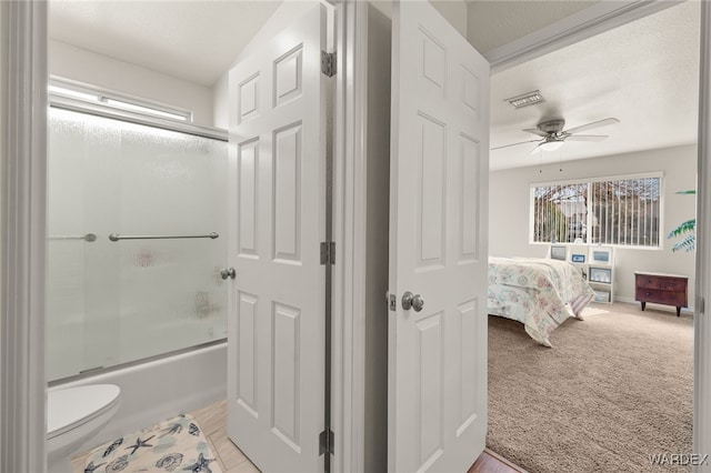 full bathroom featuring shower / bath combination with glass door, toilet, ensuite bathroom, a ceiling fan, and baseboards