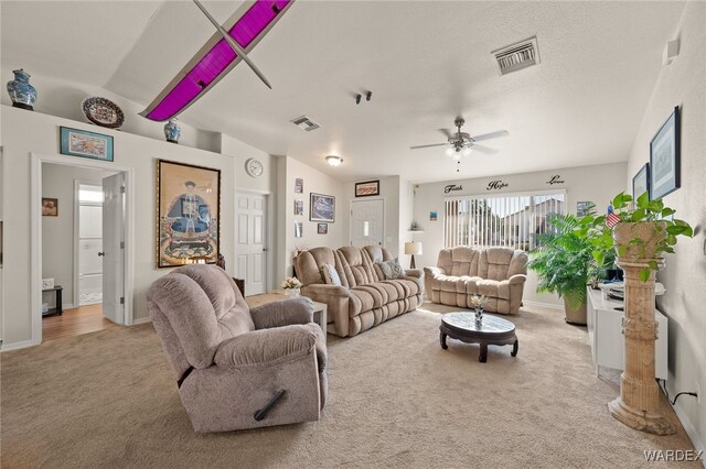 living area with light carpet, ceiling fan, visible vents, and a textured ceiling