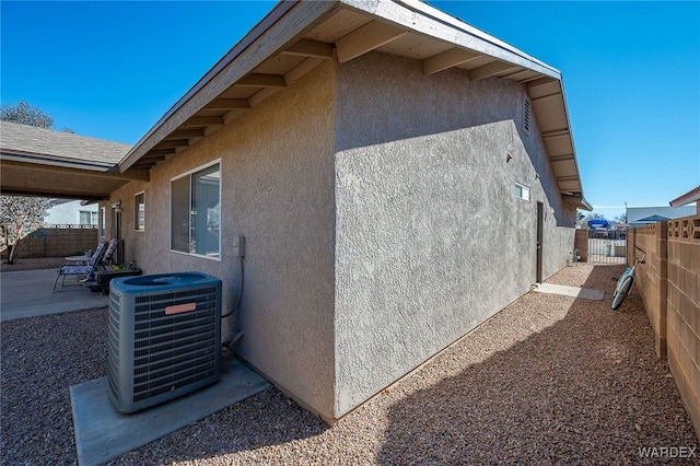 view of property exterior featuring central AC, a patio area, fence, and stucco siding