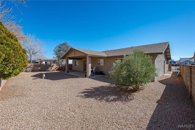 back of house with an attached carport, a patio area, a fenced backyard, and stucco siding