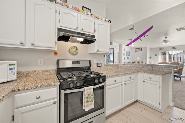 kitchen with white microwave, under cabinet range hood, a peninsula, white cabinetry, and stainless steel gas stove