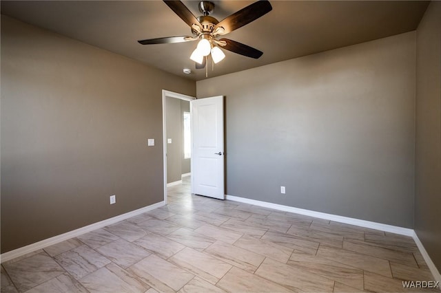 unfurnished room with ceiling fan and baseboards