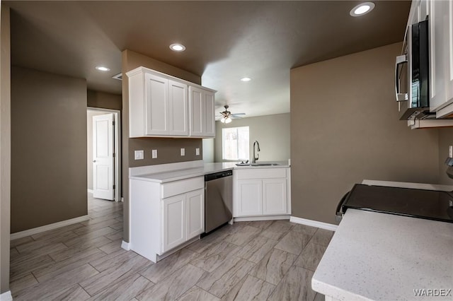 kitchen with a sink, white cabinets, stainless steel appliances, and light countertops