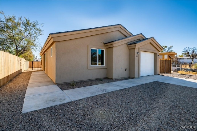 view of front of house featuring an attached garage, driveway, fence, and stucco siding