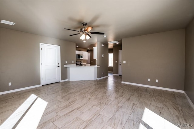 unfurnished living room with ceiling fan, visible vents, and baseboards