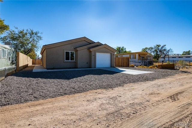 view of front of house featuring a garage, concrete driveway, and fence