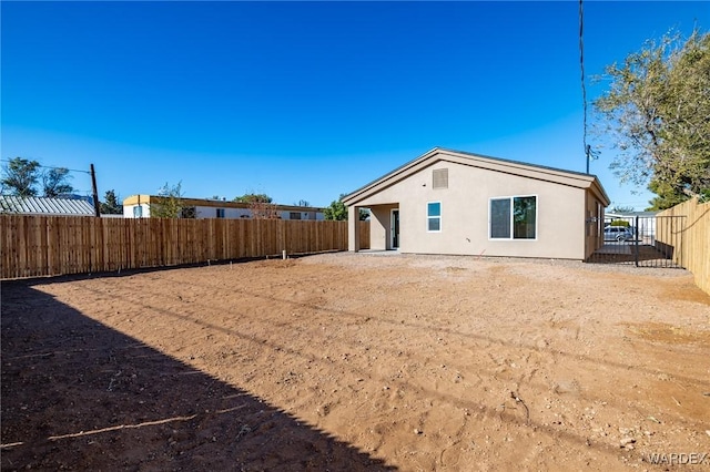 back of house with a fenced backyard and stucco siding