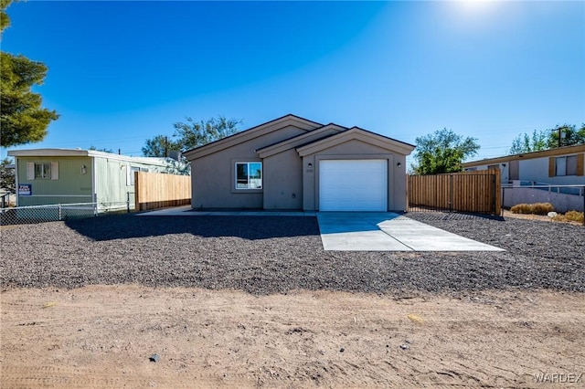 view of front facade featuring concrete driveway, fence, and an attached garage