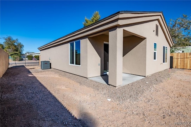 rear view of house featuring central air condition unit, stucco siding, a fenced backyard, and a patio