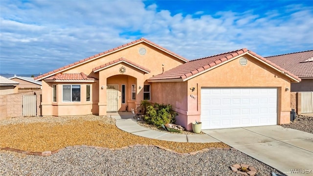 mediterranean / spanish-style house with a tile roof, concrete driveway, a garage, and stucco siding