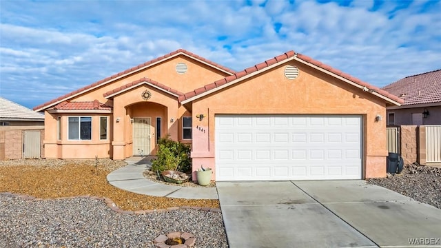 mediterranean / spanish home featuring a tiled roof, a garage, driveway, and stucco siding