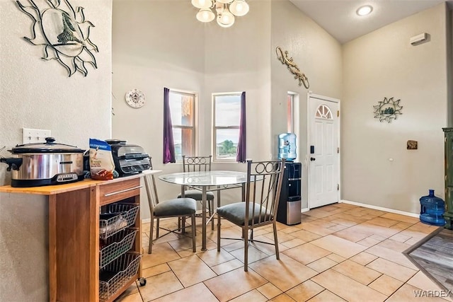 dining area with light tile patterned flooring, a chandelier, baseboards, and a towering ceiling