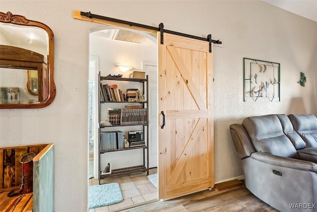 living area featuring a barn door, wood finished floors, visible vents, and arched walkways