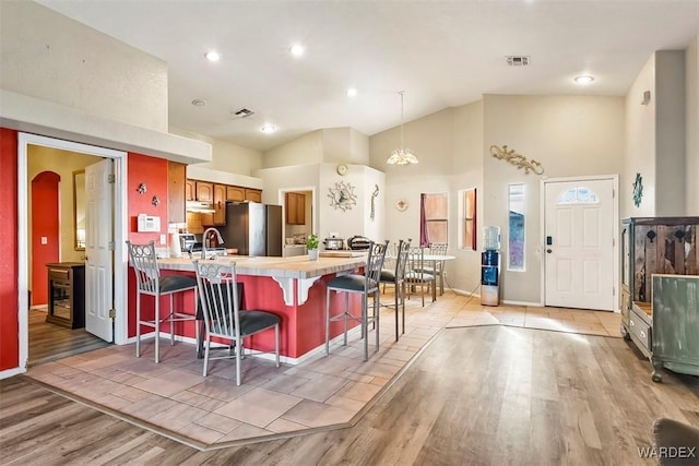 kitchen featuring visible vents, a peninsula, light wood-style flooring, appliances with stainless steel finishes, and a kitchen breakfast bar