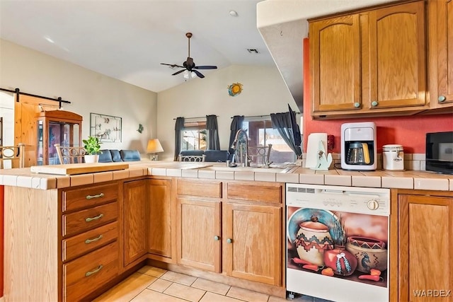 kitchen featuring a ceiling fan, open floor plan, tile countertops, a peninsula, and dishwashing machine