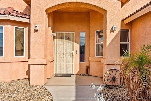 property entrance with a tiled roof and stucco siding