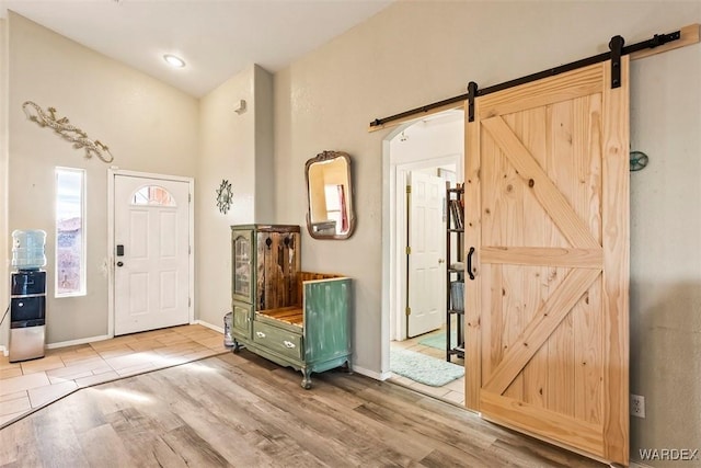 foyer entrance with baseboards, a barn door, and wood finished floors