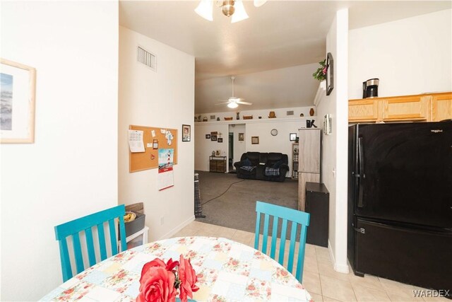 dining room featuring visible vents, light carpet, a ceiling fan, light tile patterned floors, and lofted ceiling