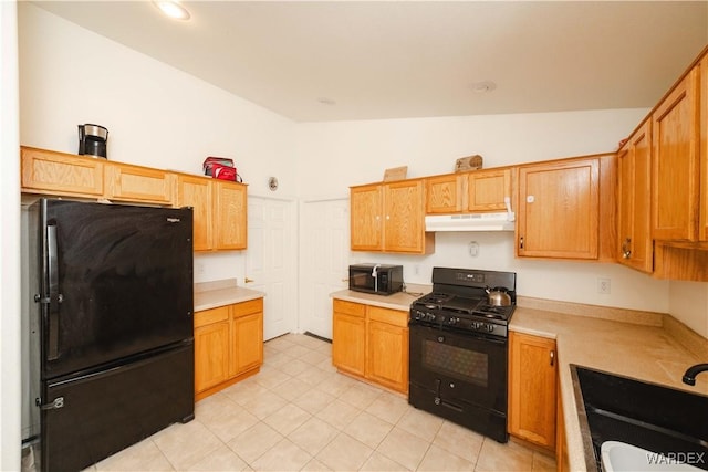 kitchen with a sink, black appliances, light countertops, vaulted ceiling, and under cabinet range hood