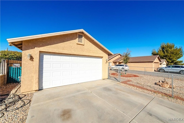 exterior space with a gate, stucco siding, and fence