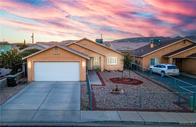 view of front of house featuring a fenced front yard, concrete driveway, an attached garage, and stucco siding