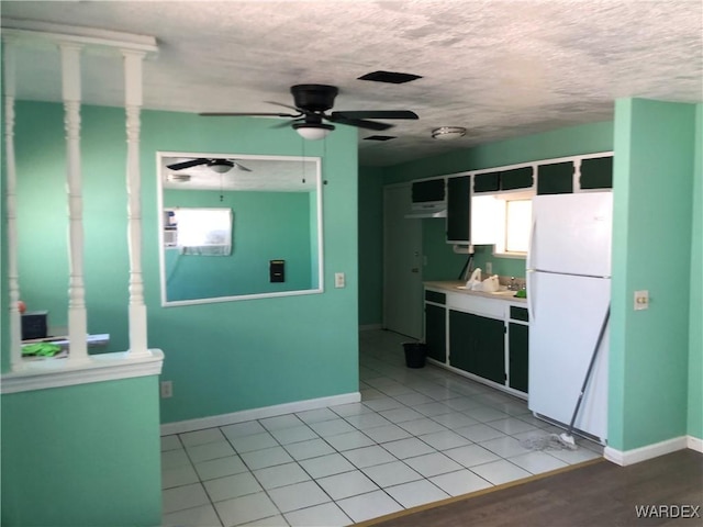 kitchen featuring a textured ceiling, a sink, a ceiling fan, baseboards, and freestanding refrigerator