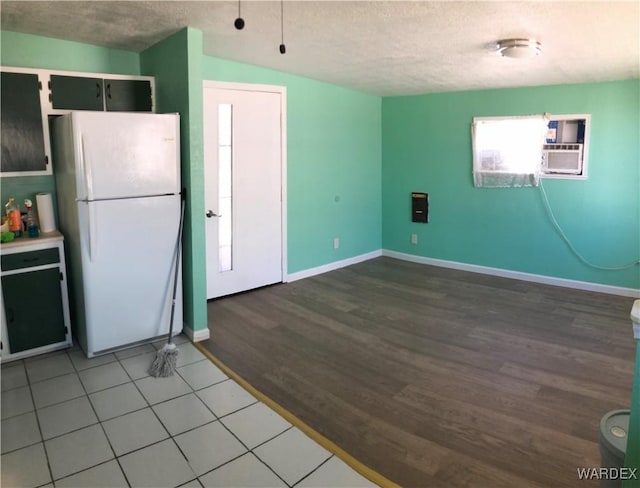 kitchen featuring light countertops, freestanding refrigerator, a textured ceiling, wood finished floors, and baseboards