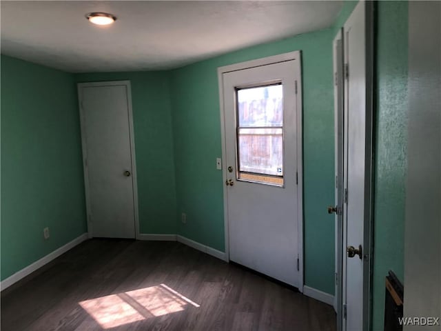 spare room with dark wood-style flooring and baseboards