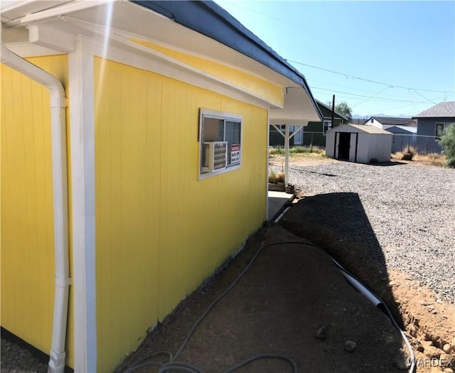 view of side of home featuring an outbuilding, a shed, and fence