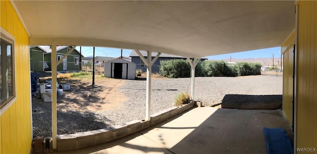 view of patio / terrace with a storage unit, an outdoor structure, and fence