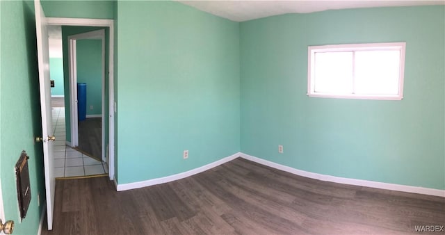 empty room featuring baseboards and dark wood finished floors