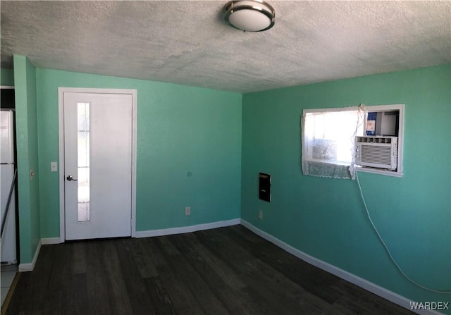 spare room featuring a textured ceiling, dark wood-type flooring, and baseboards