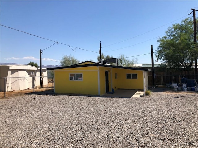 rear view of house with fence and stucco siding