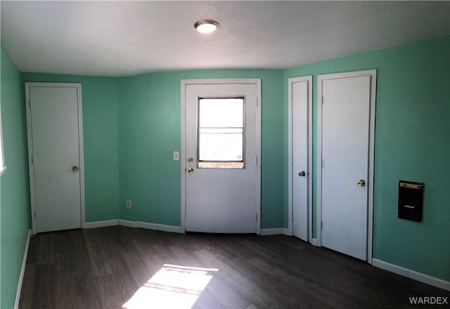 spare room featuring dark wood-style floors and baseboards