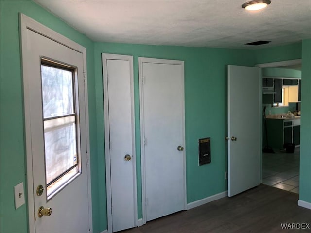 unfurnished bedroom featuring dark wood-style flooring, two closets, and baseboards